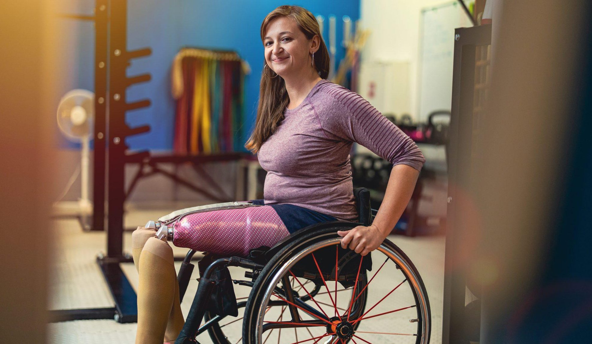 Picture of a woman in a wheelchair with prosthetics on, in the gym
