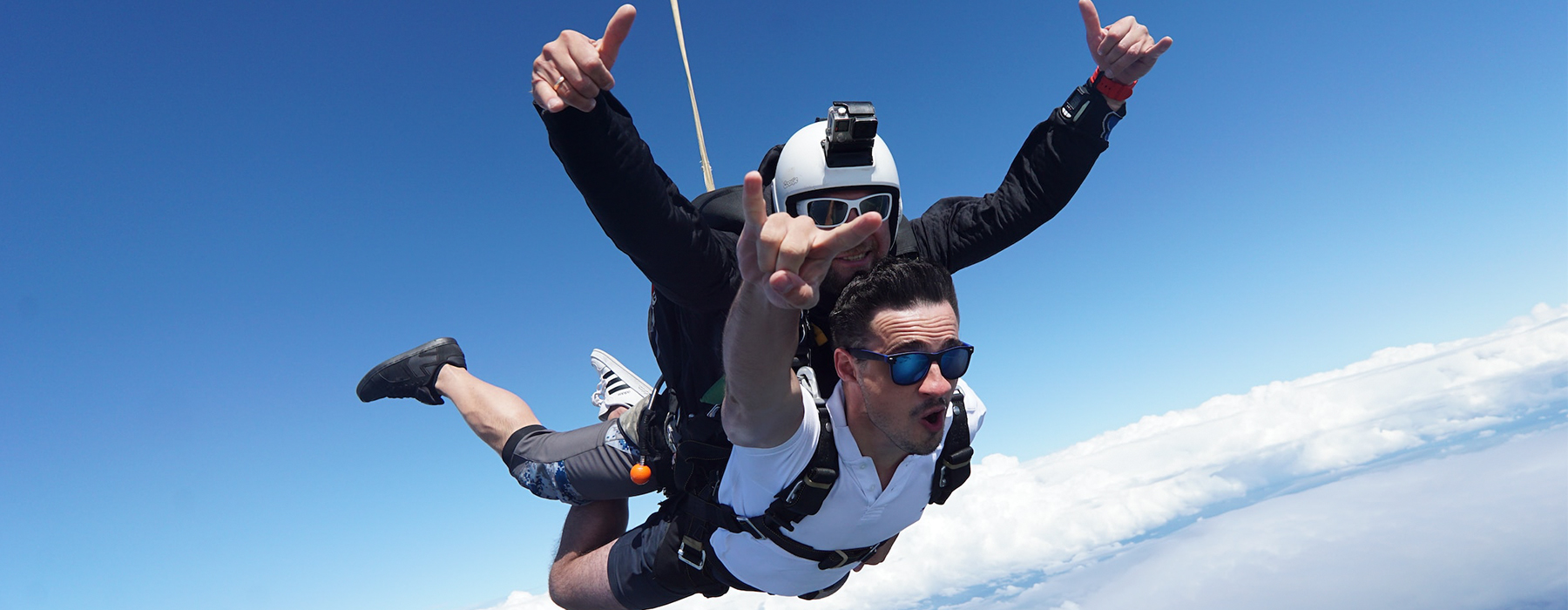 Two people tandem skydiving and posing through the air